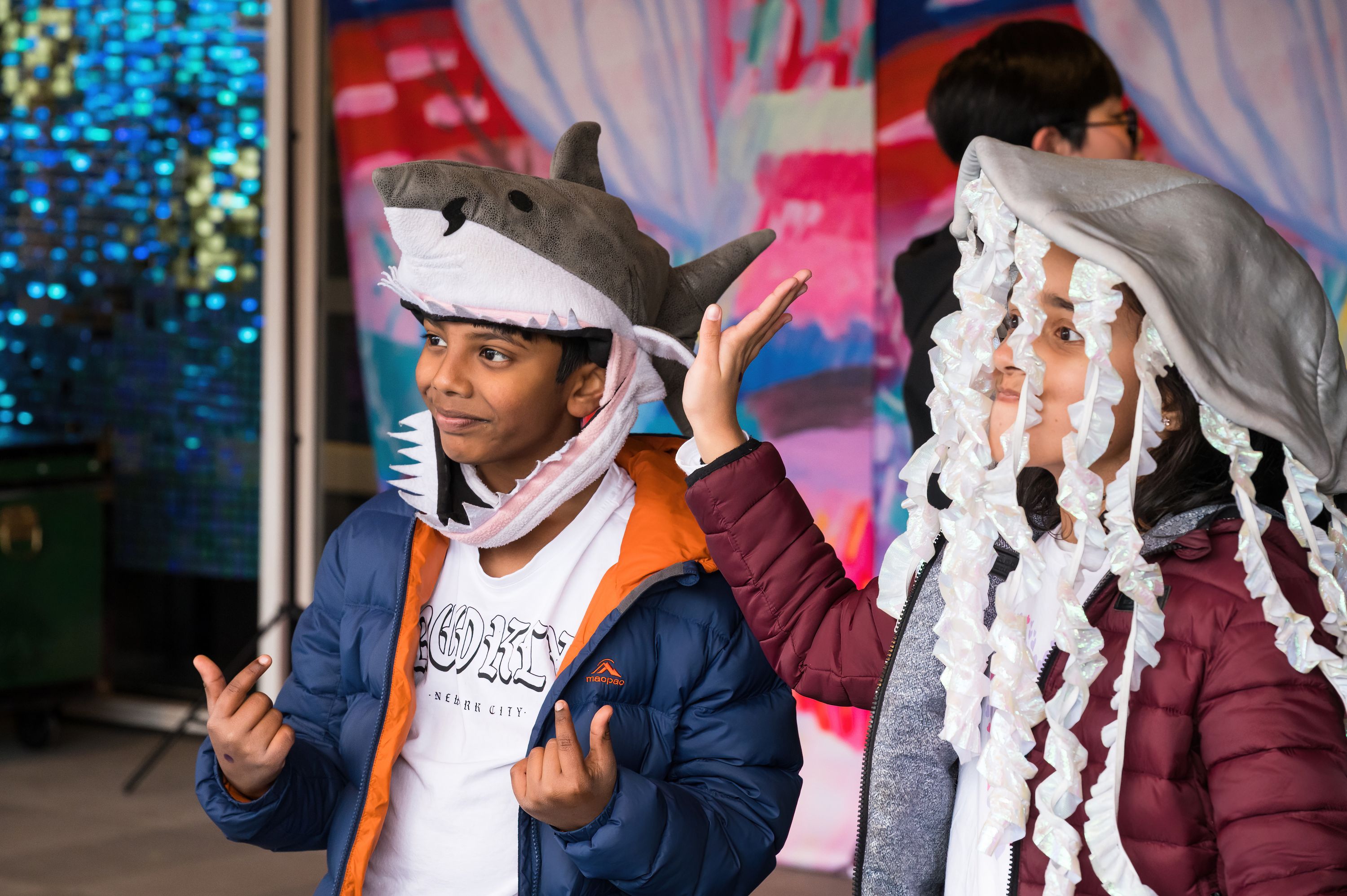 Two children wearing dress up hats (a shark and a jellyfish) while posing for a photo.