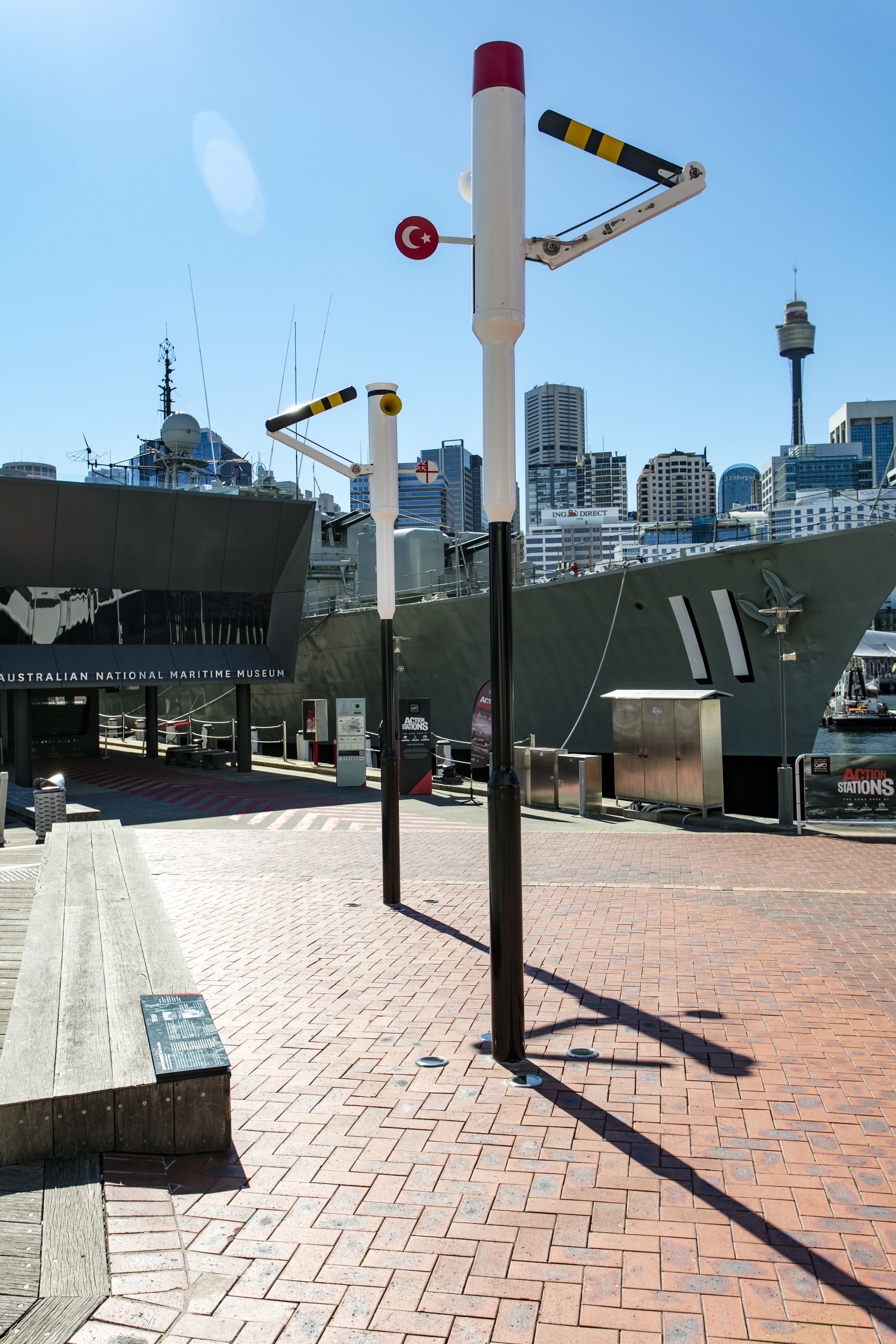 Photo of two sculptures which are black and white poles with moving train signals from one side. 