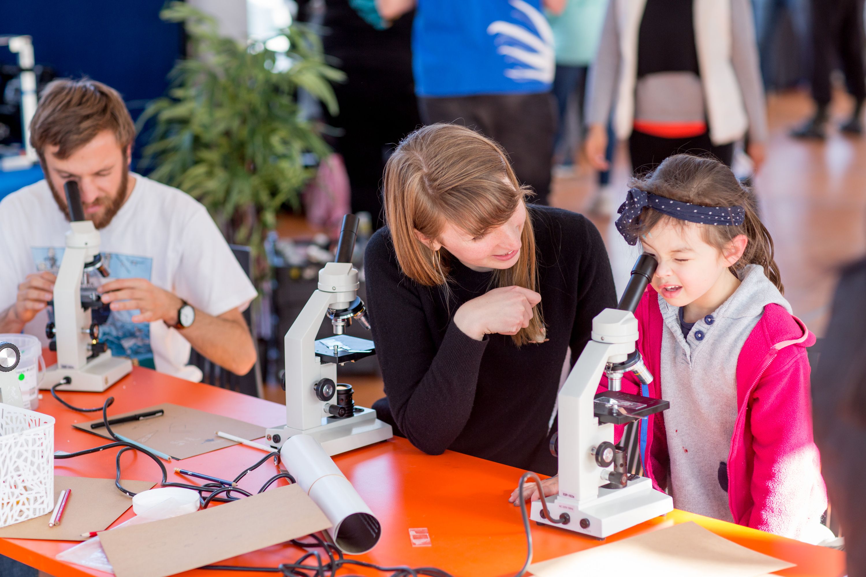 Photo of a woman with a girl looking through a microscope
