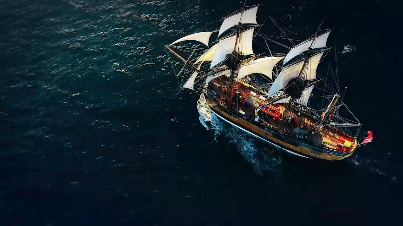 Overhear shot of replica Endeavour tall ship, sailing with large white sails on a dark blue green ocean.