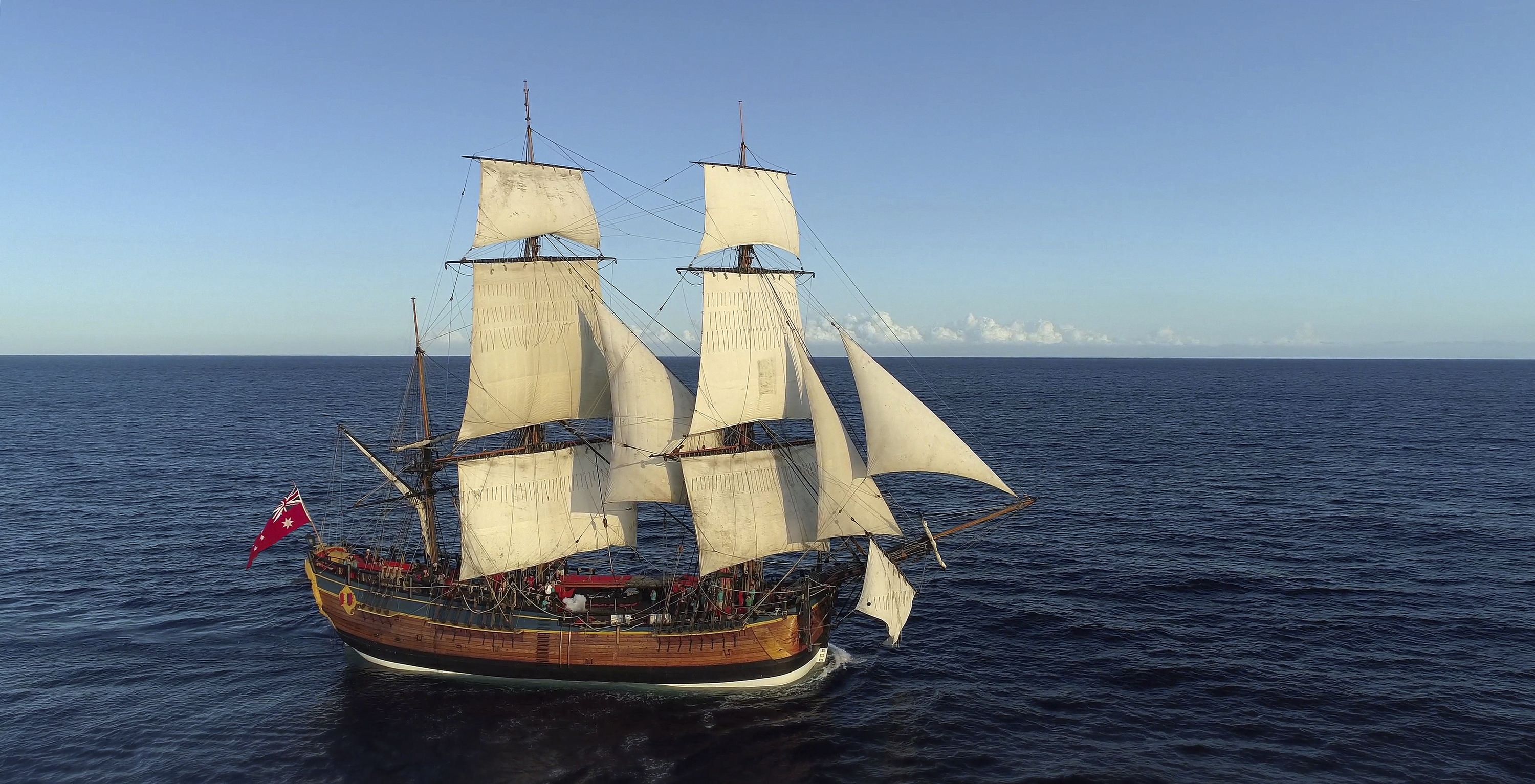 Photo of a tall ship at sea with sails raised.