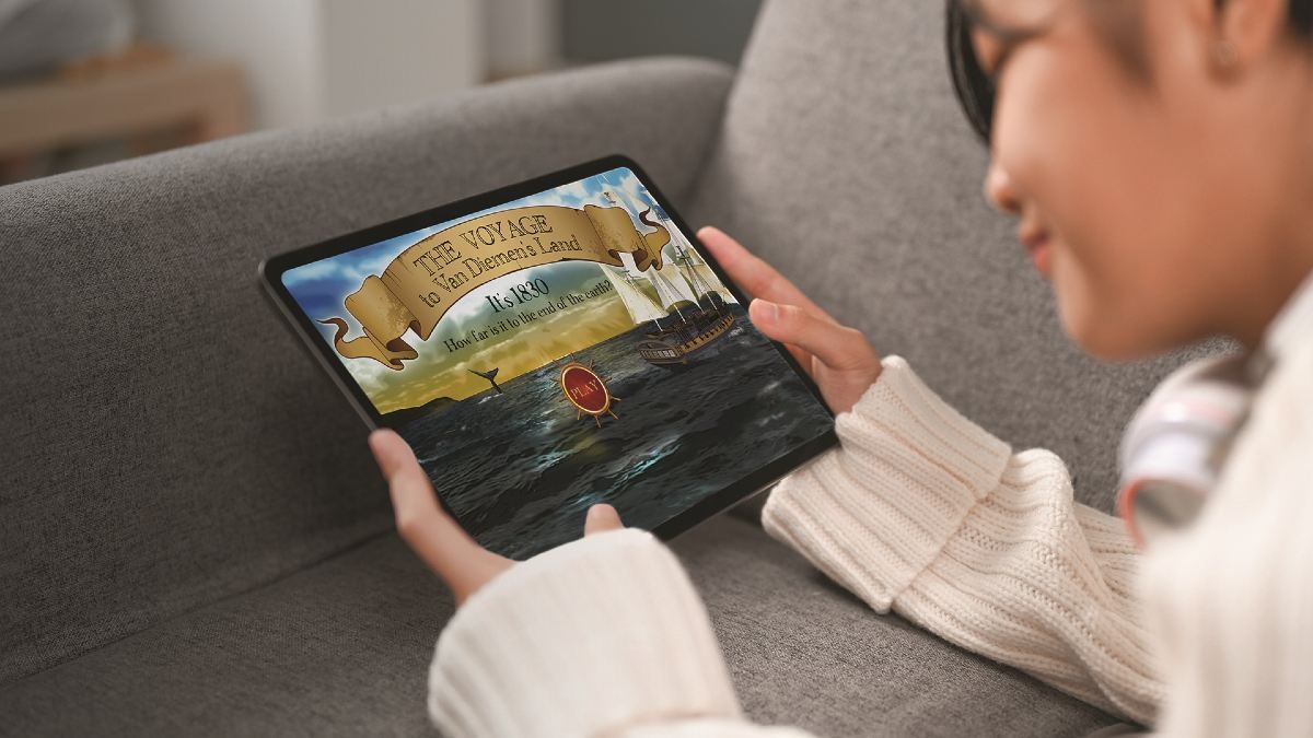 Photo of a girl holding an iPad with a game on the screen call The Voyage.